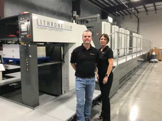 WorldPressOnline shown here todd and brandy frost of next day four color pause in front of komori press that is equipped with xo series uv led technology from ams spectral uv a baldwin technology company 5995ac350d18b